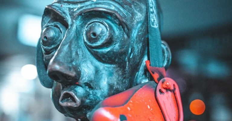 The close up of a face of a metal statue with wide eyes and shocked expression