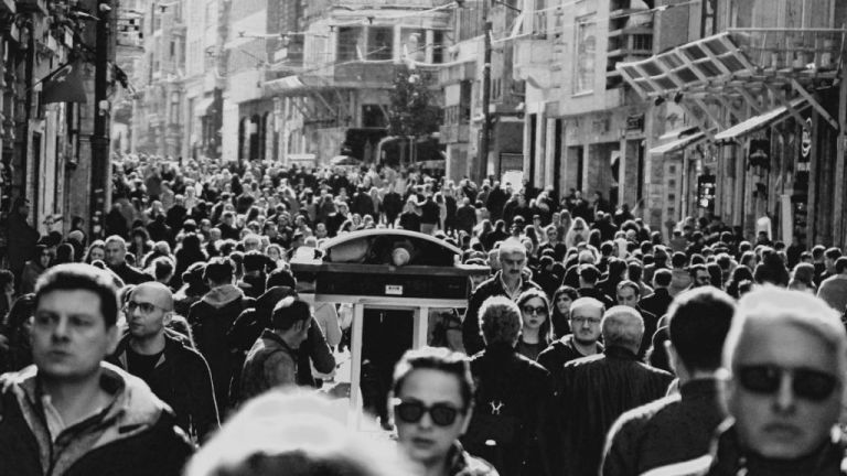 A black and white image of a street in a marketplace crowded with pedestrians